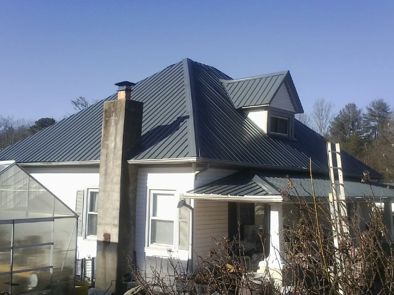 Dark blue standing seam metal roof on a white farmhouse with dormer — Slate & Tile Roof Repair by Roofing Brothers in Warrenville