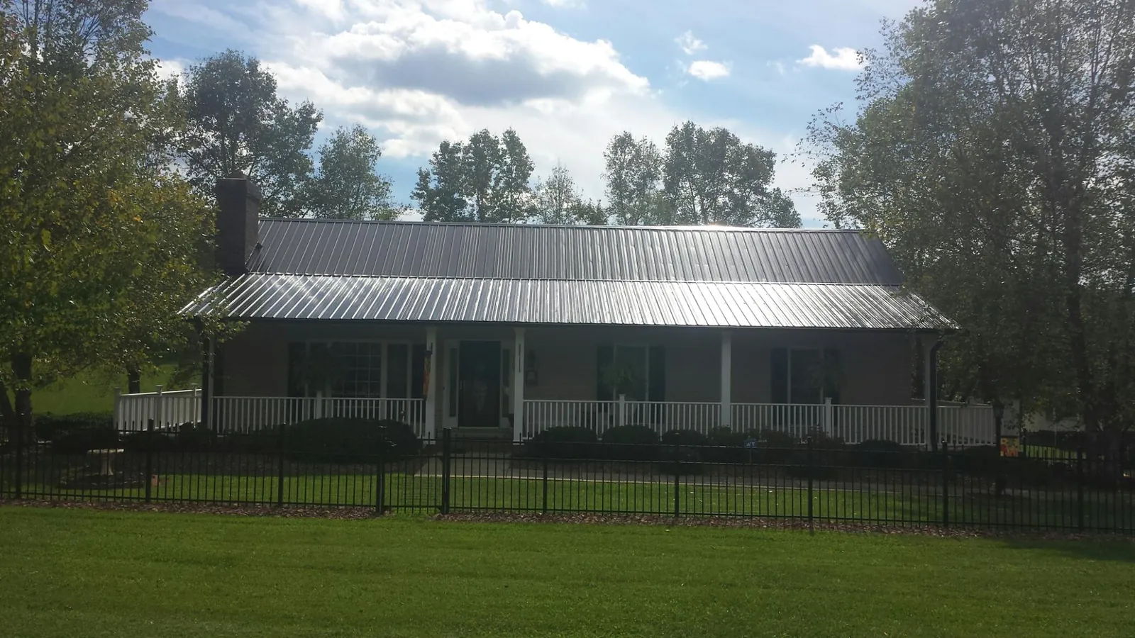 Gray metal roof on a brick ranch with a full width front porch — Gutter Guard Installation work by our crew in Warrenville